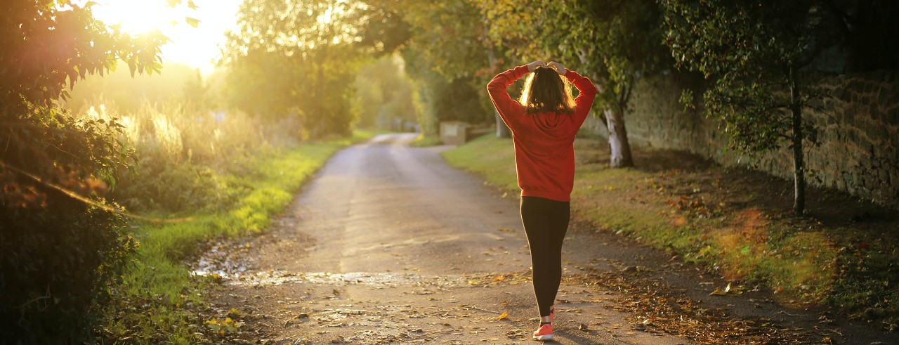 Woman walking on scenic road during sunrise