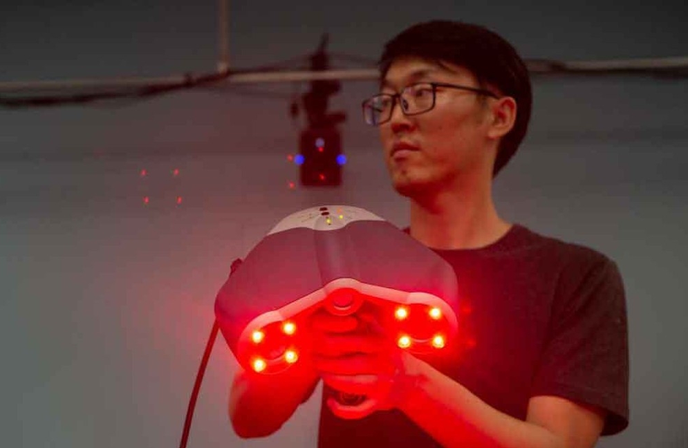 A student holds up a laser scanner used in smart aviation manufacturing.