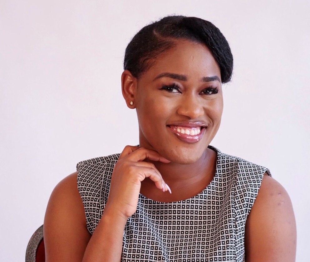 Student sitting and smiling with a hand to her face.