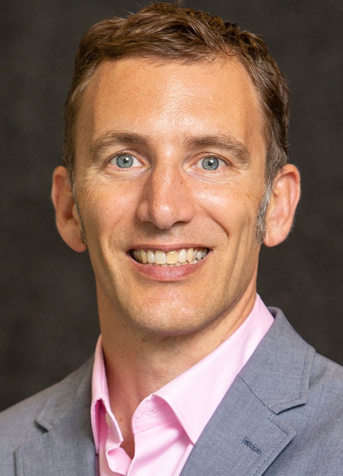 head shot of a white man in a jacket and button-down shirt