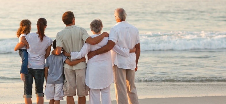 family seem from behind on a beach: grandparents, parents and 2 kids