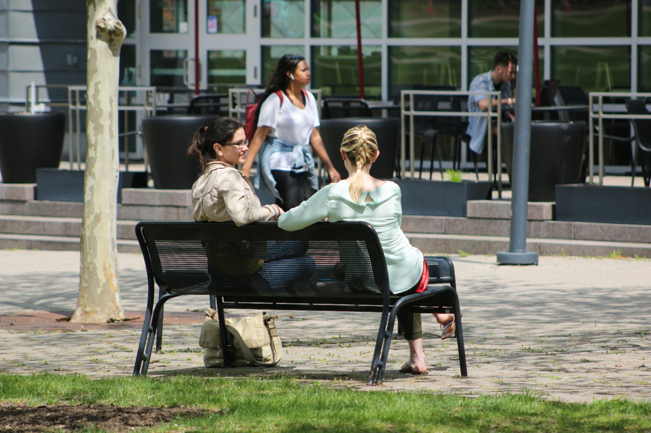 Two women sit on a bench and chat