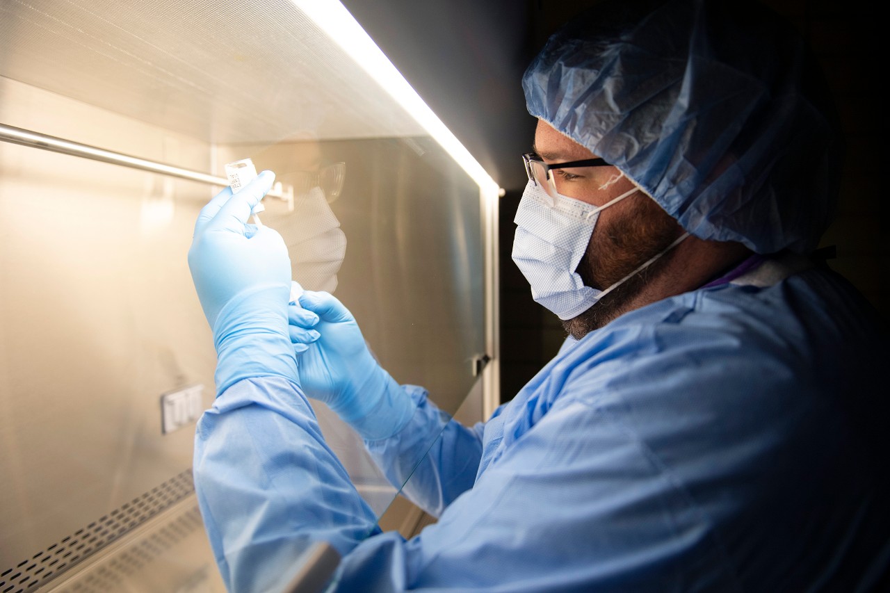 a male pharmacist prepares a dose of a vaccine in a lab
