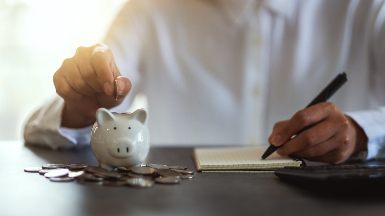 person putting coins in a piggy bank
