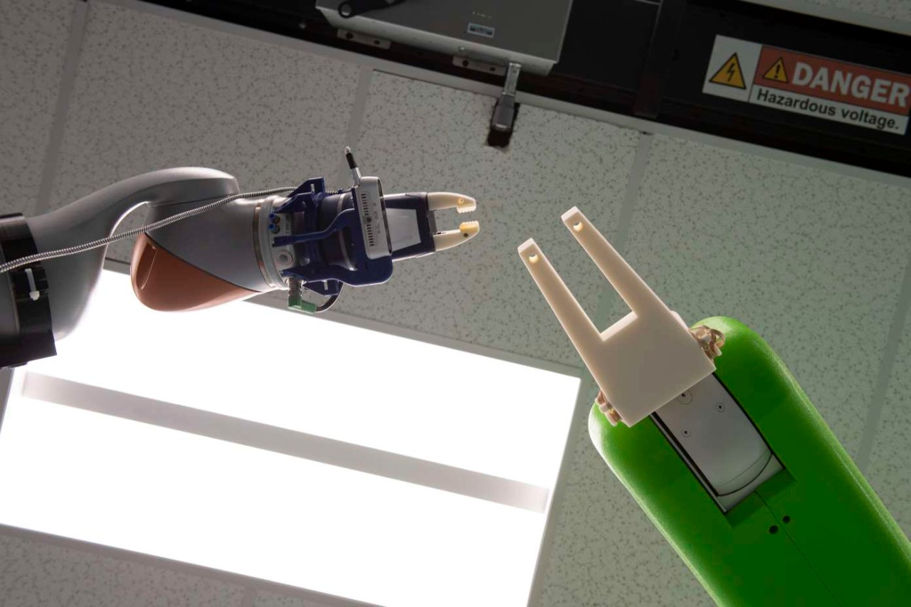 Two robotic hands nearly touch.
