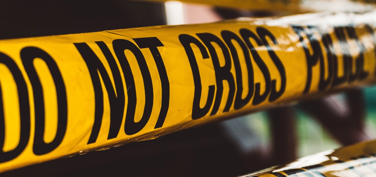 yellow crime tape saying Do Not Cross Police