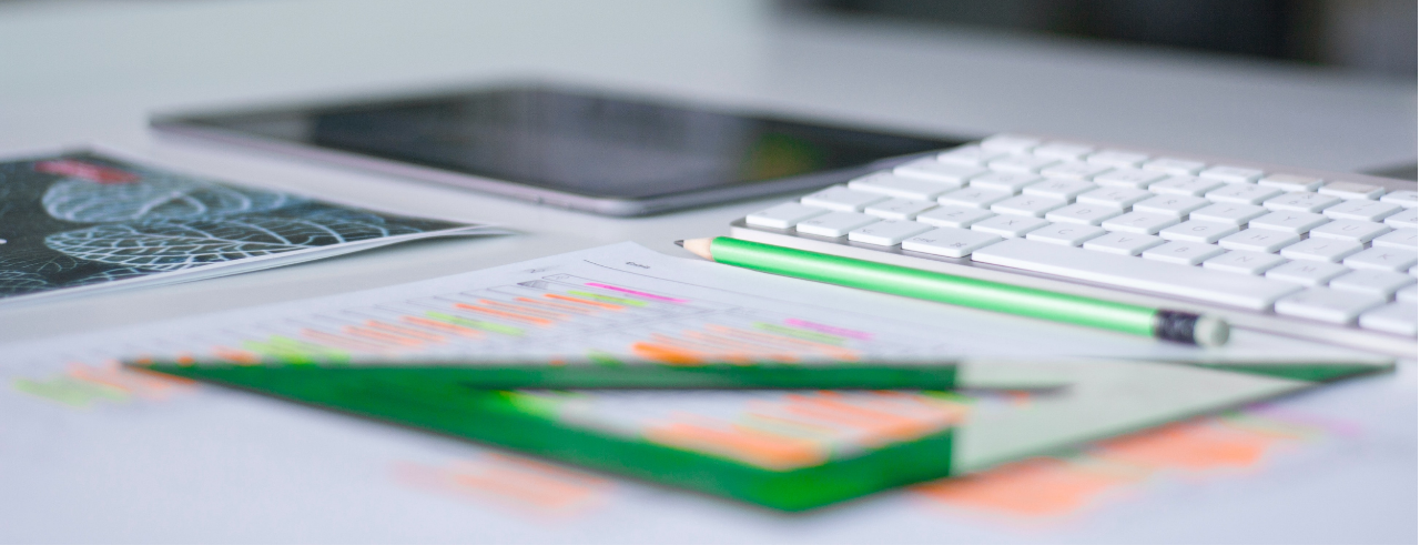 a computer keyboard, tablet, papers, pencil and protractor sit on a desk