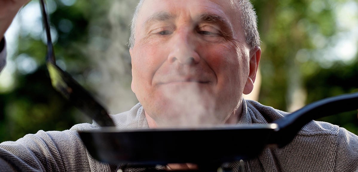 a man smelling food cooking on a skillet