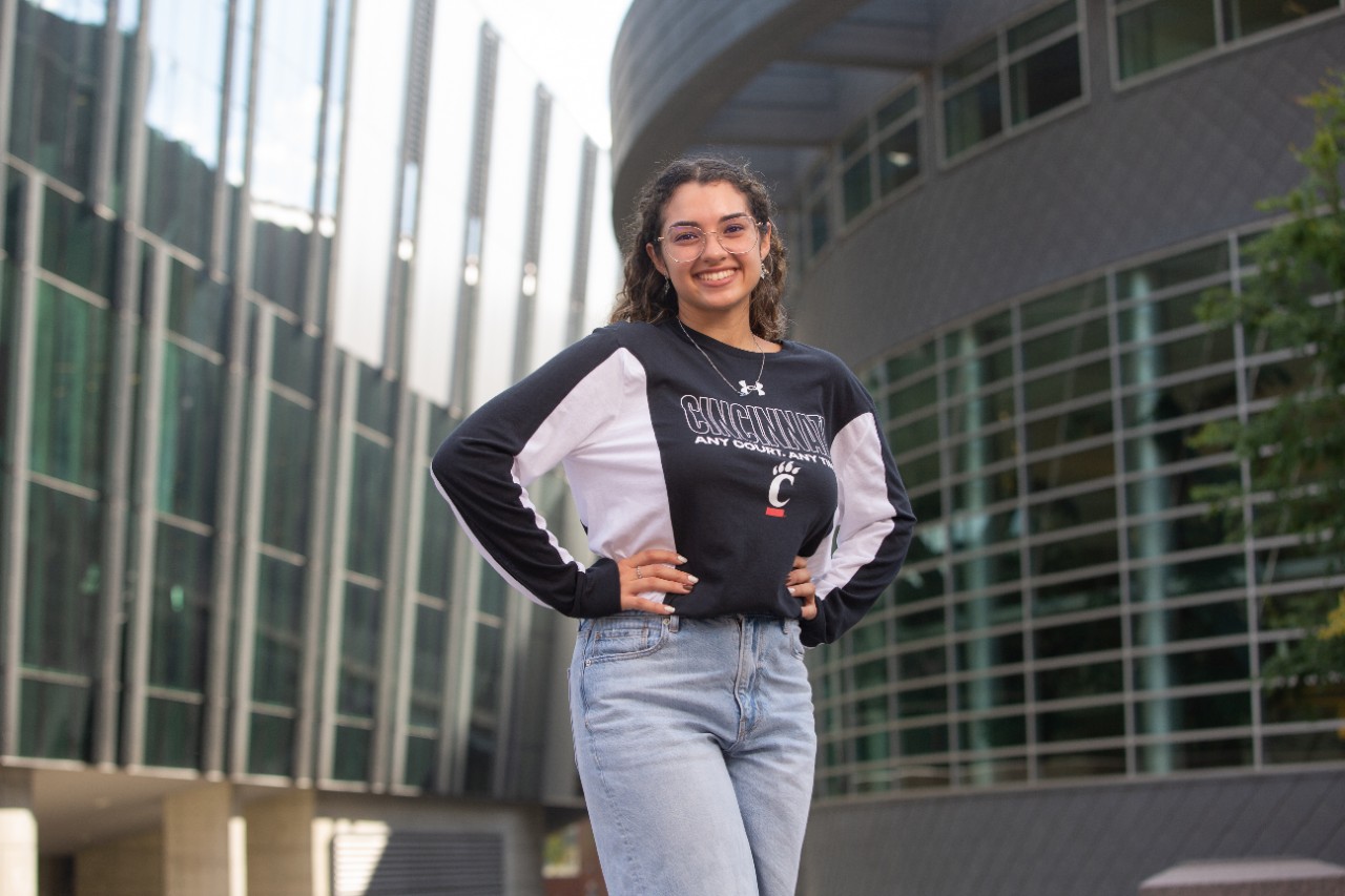 A woman stands in front of a building.