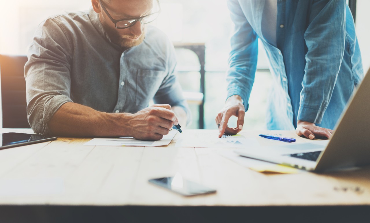 Two coworkers working process photo.Young woman working together with colleague at modern office loft.Teamwork concept.Blurred background.Horizontal