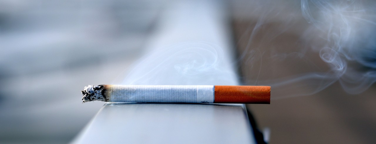 cigarette burning on a table ledge outside 