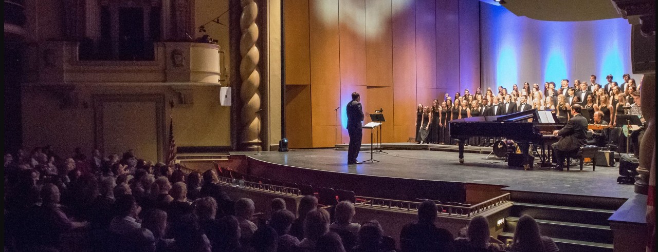 Alex Gartner conducts a choir on stage