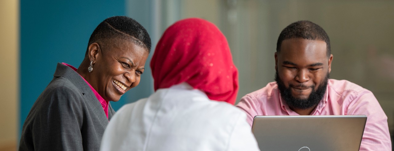 Pat Achoe and students talk while seated at a table