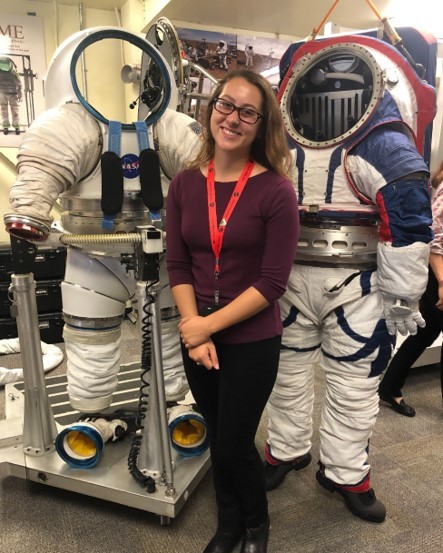 Anna Lanzillotta standing with NASA space suits