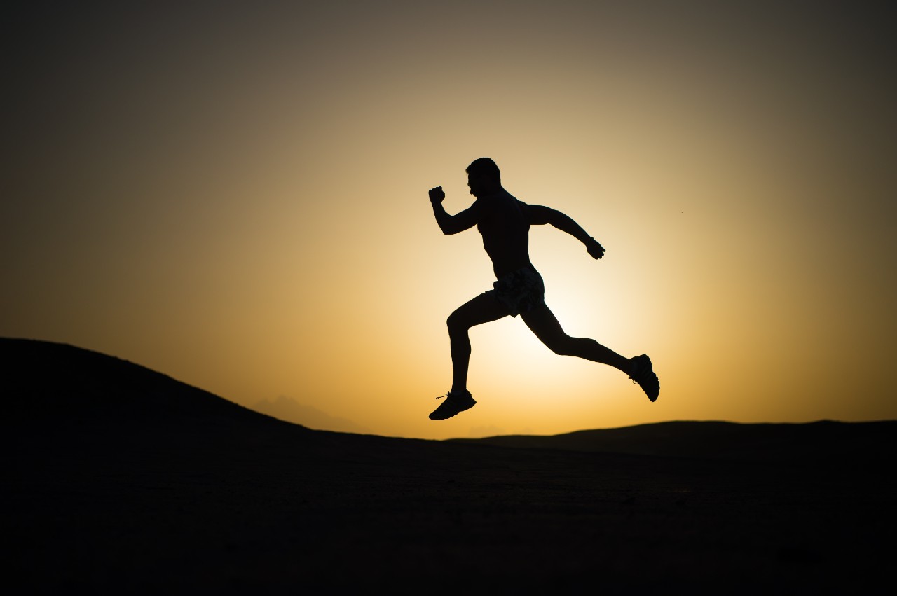 runner. silhouette of running man on sunset fiery sky background in mountain, sport and recreation, future and success, people and nature, speed and healthy lifestyle