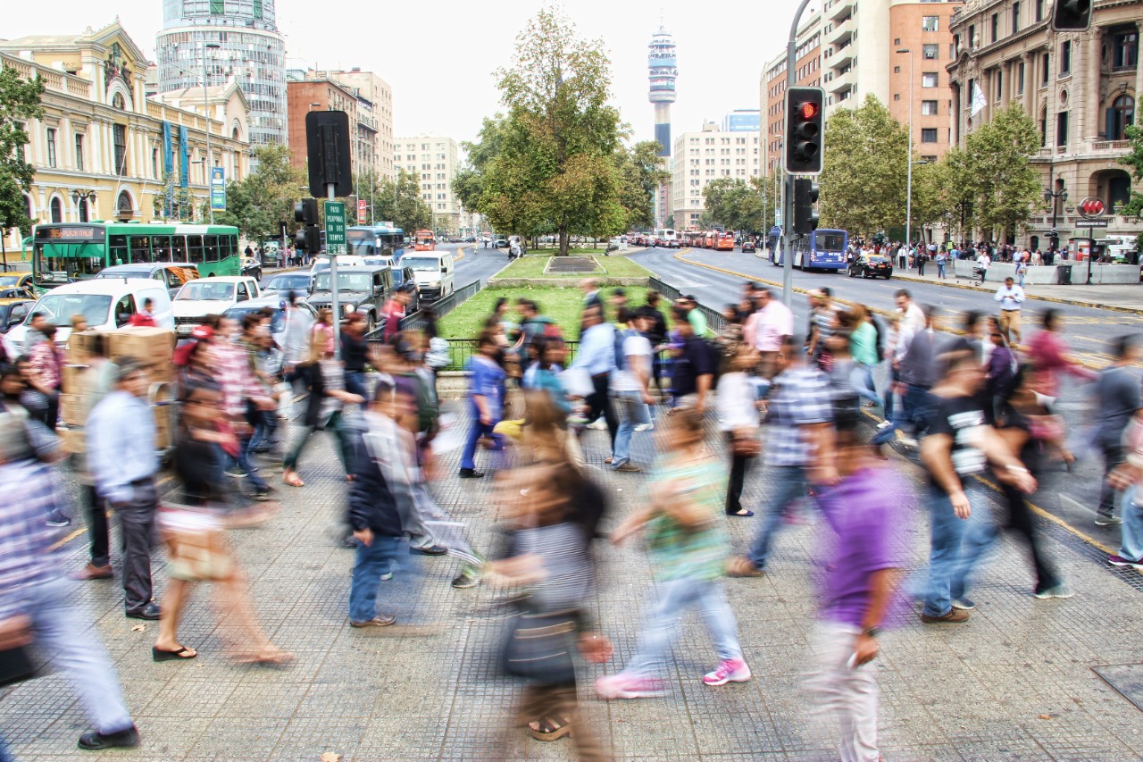 A motion-blurred image of a crowded street full of pedestrians.