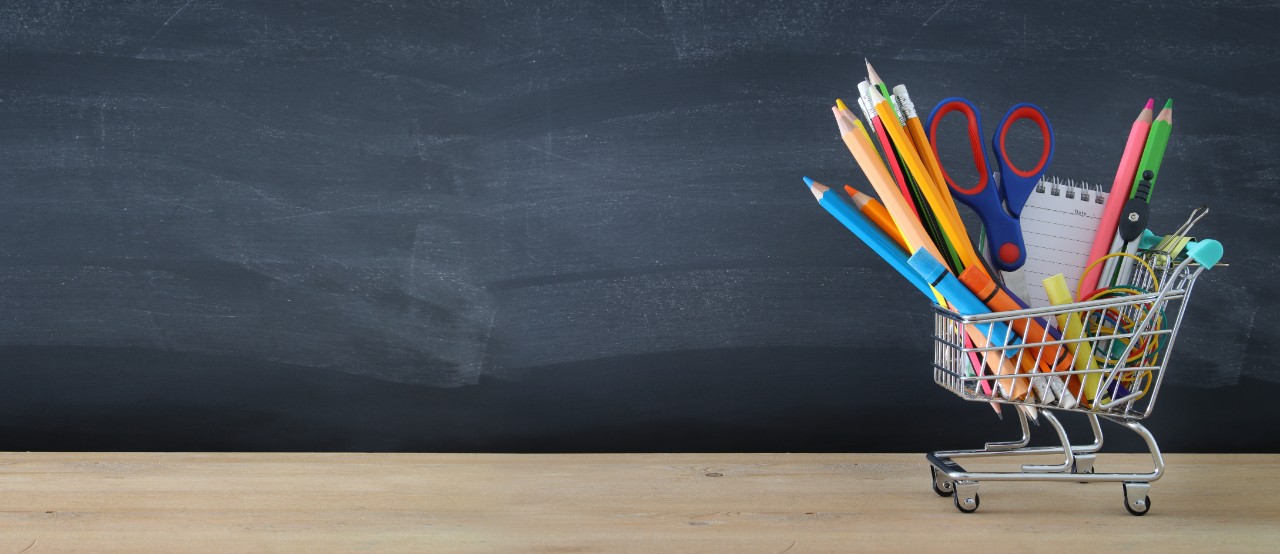 A stock image of school supplies in a shopping cart.