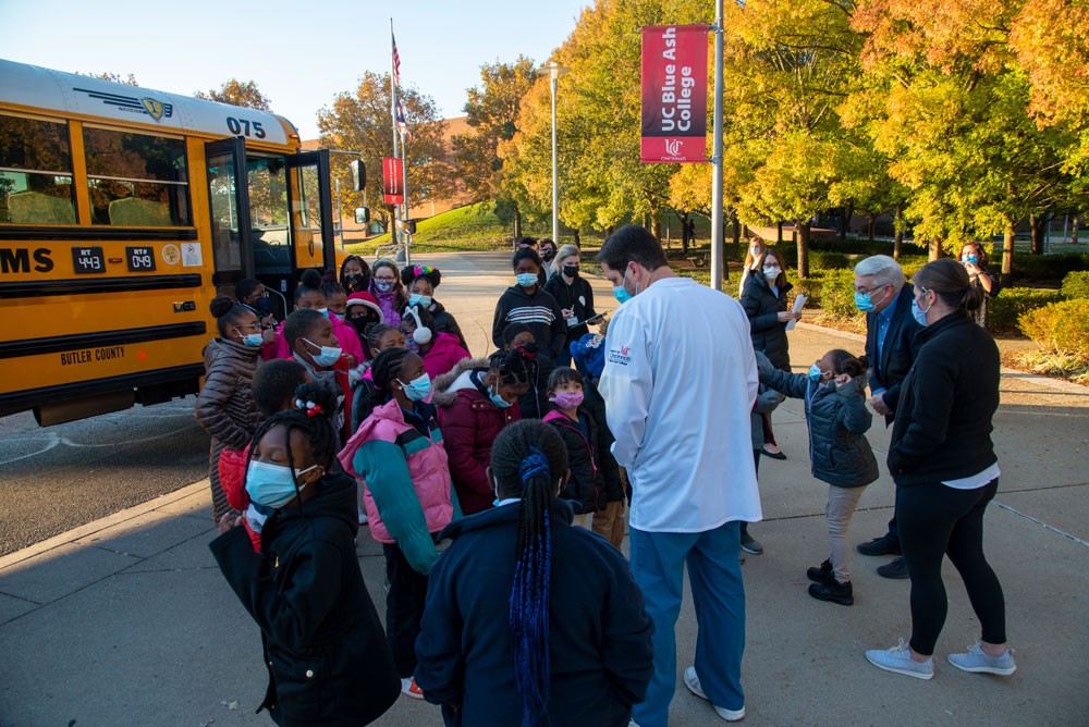 Masked schoolchildren getting off a school bus at UC Blue Ash campus