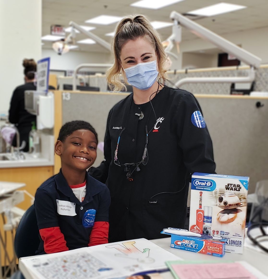 Smiling child with masked dental hygienist