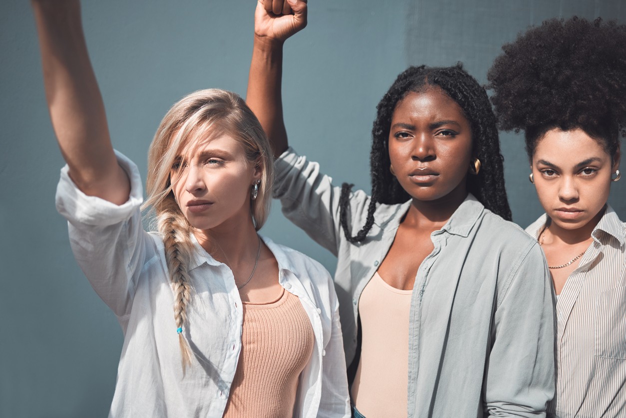 Diverse group of women advocates stand with open raised fists. 