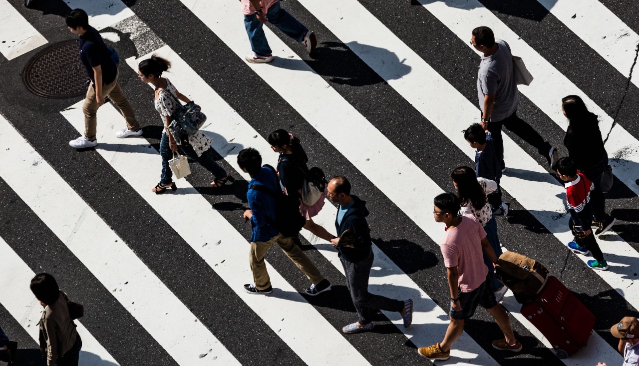 People walking 6ft apart on black and white roadway  