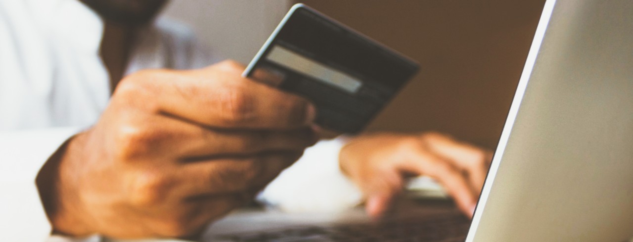 A man looking at a credit card and laptop.