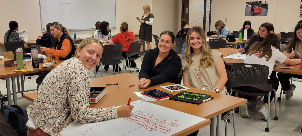 Elementary Education students smile together during a group project.