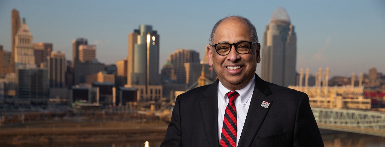 UC President Neville G. Pinto in front of Cincinnati skyline and Ohio River