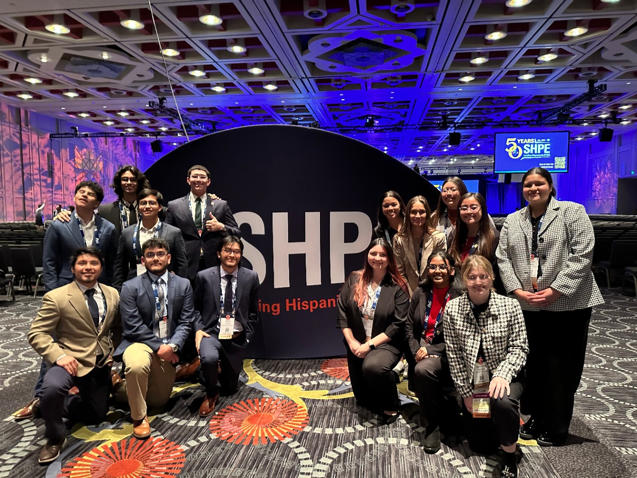 UC students at the SHPE annual conference pose in front of a SHPE sign. 