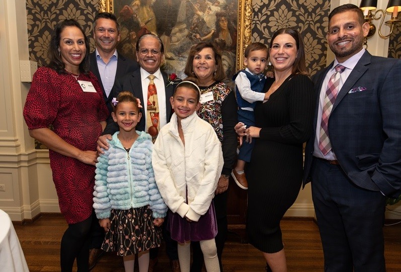 three women, three men and three young children, wearing dresses and suits, pose together