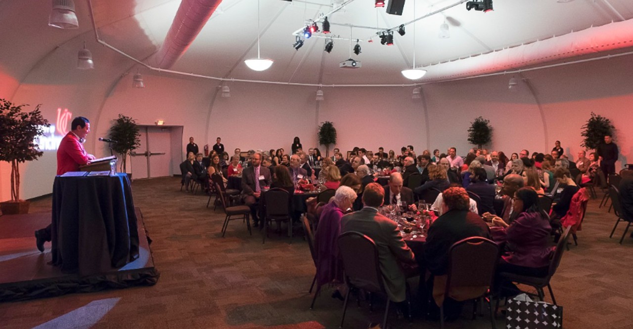 A speaker at the dais addresses people gathered at a gala.