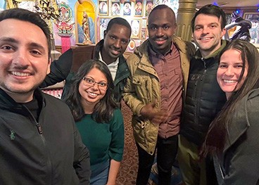 A group of smiling people, including Niyigena and Muvunyi take a selfie in a colorful restaurant