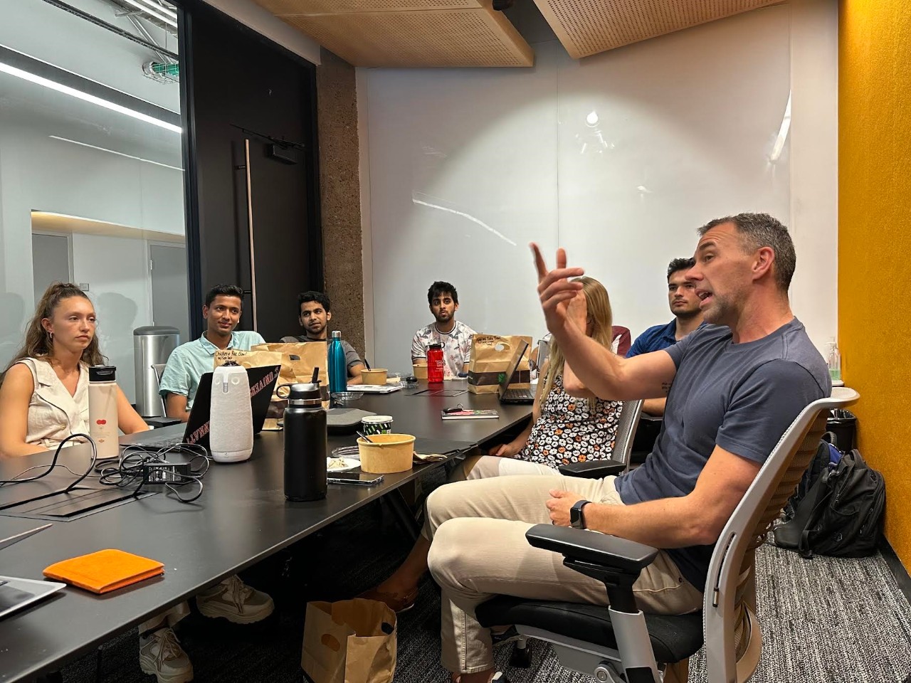 A group of students in the Venture Lab NEXT program meets with mentors around a conference table.
