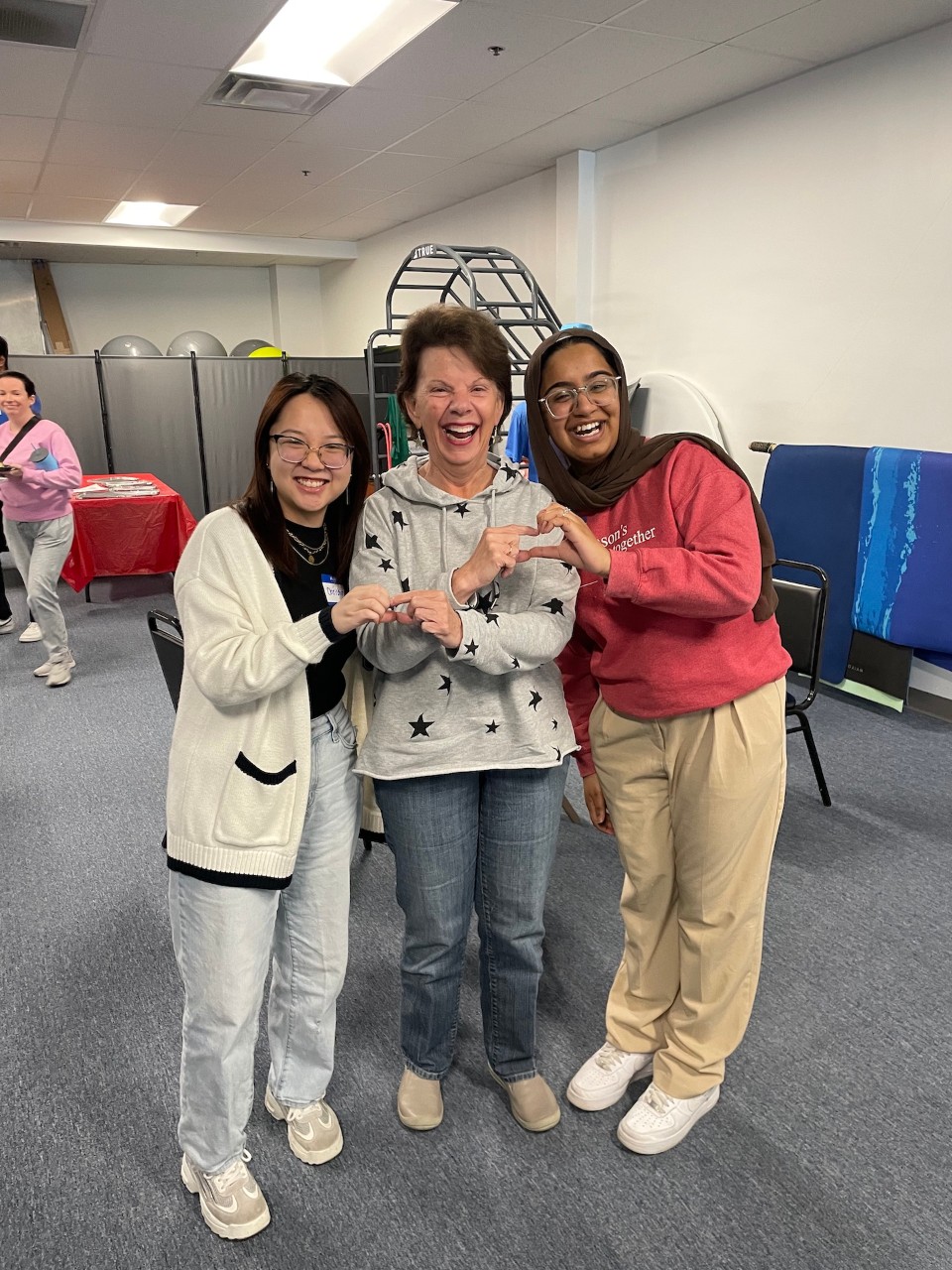 Two students and a Parkinson Community fitness member stand and smile
