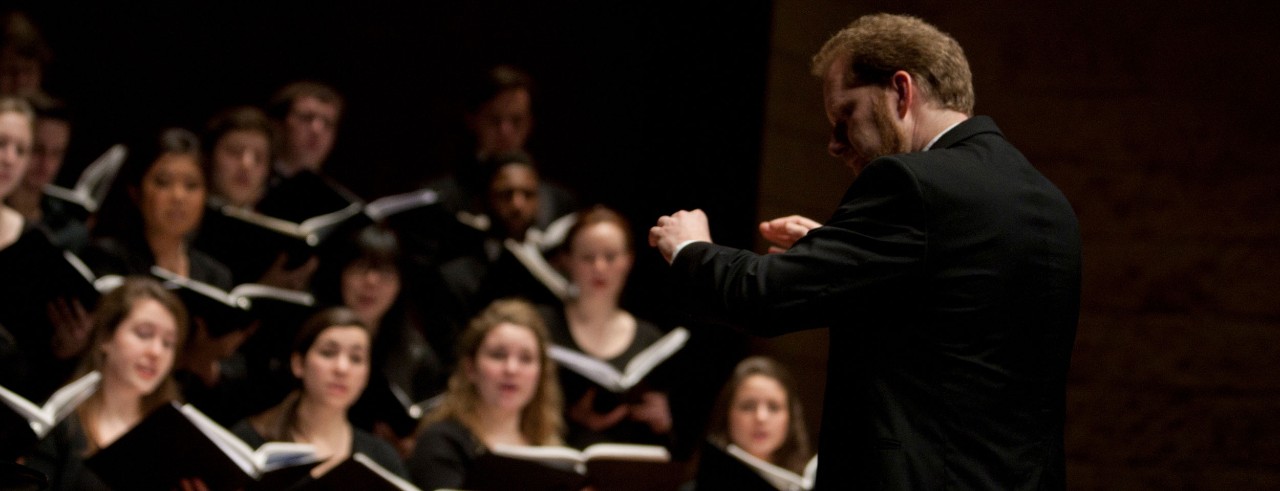 Brett Scott conducting the CCM Chorale on stage.