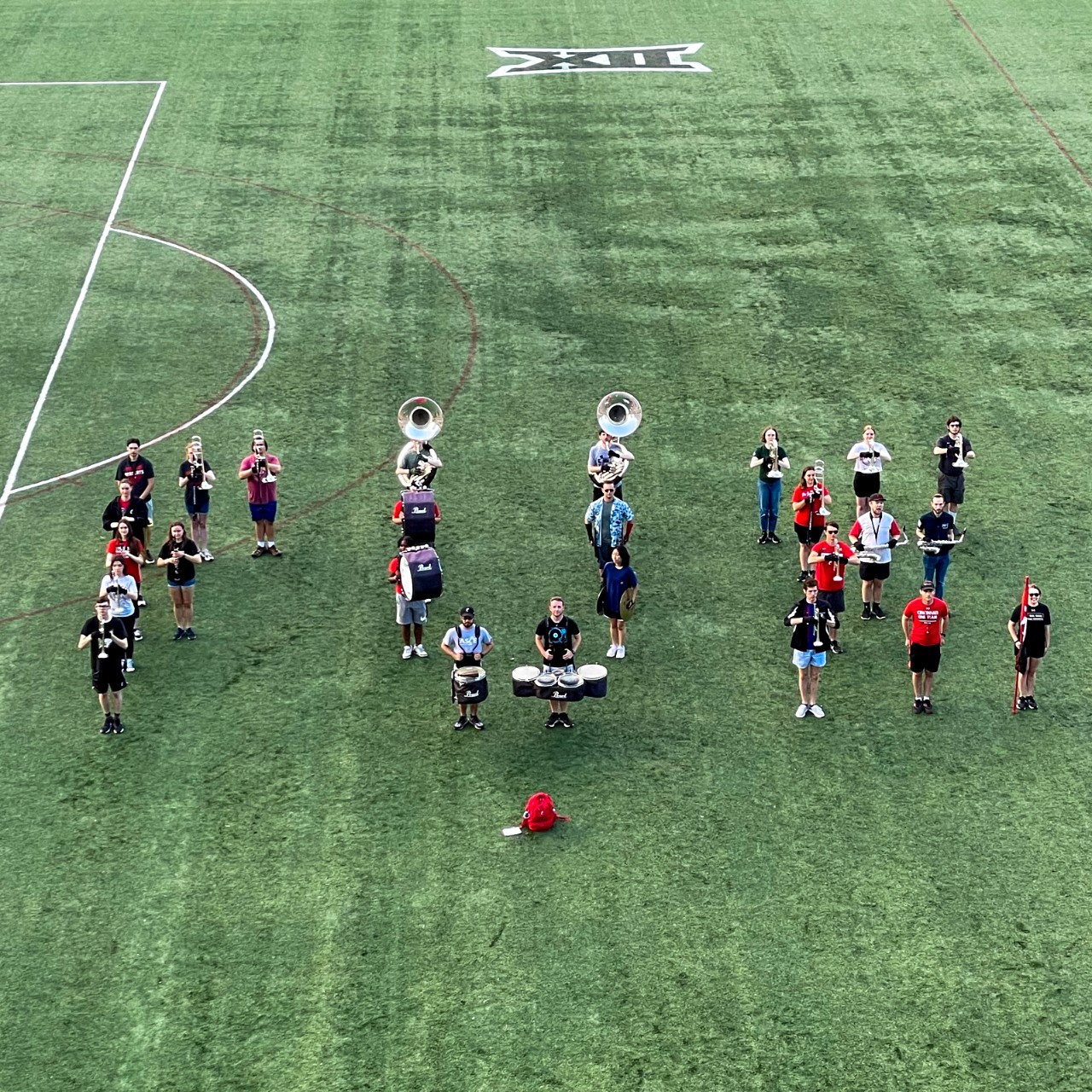 Members of the marching band form the letters "FUE" on a soccer field.