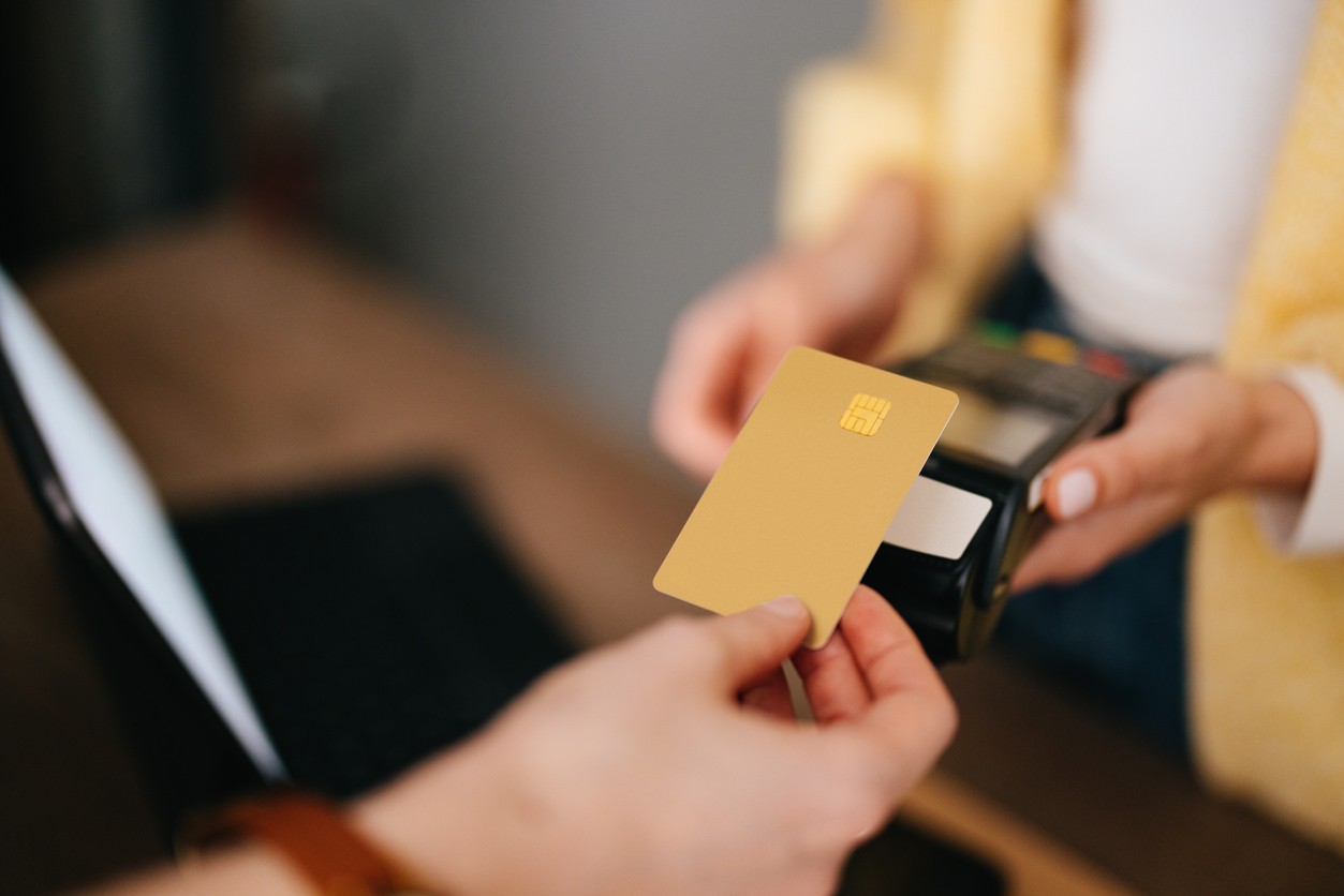Woman holding credit card reader while customer paying bill using contactless payment.