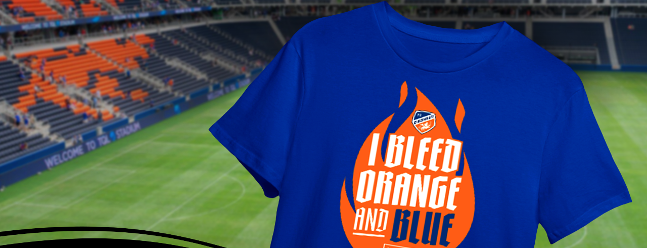 A blue T-shirt that says "I bleed orange and blue" is in the foreground, with FC Cincinnati's TQL Stadium in the background