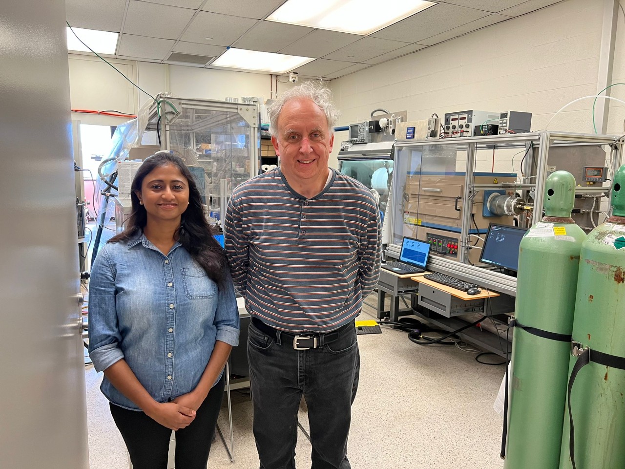 A man and a woman stand in a science laboratory and smile at the camera