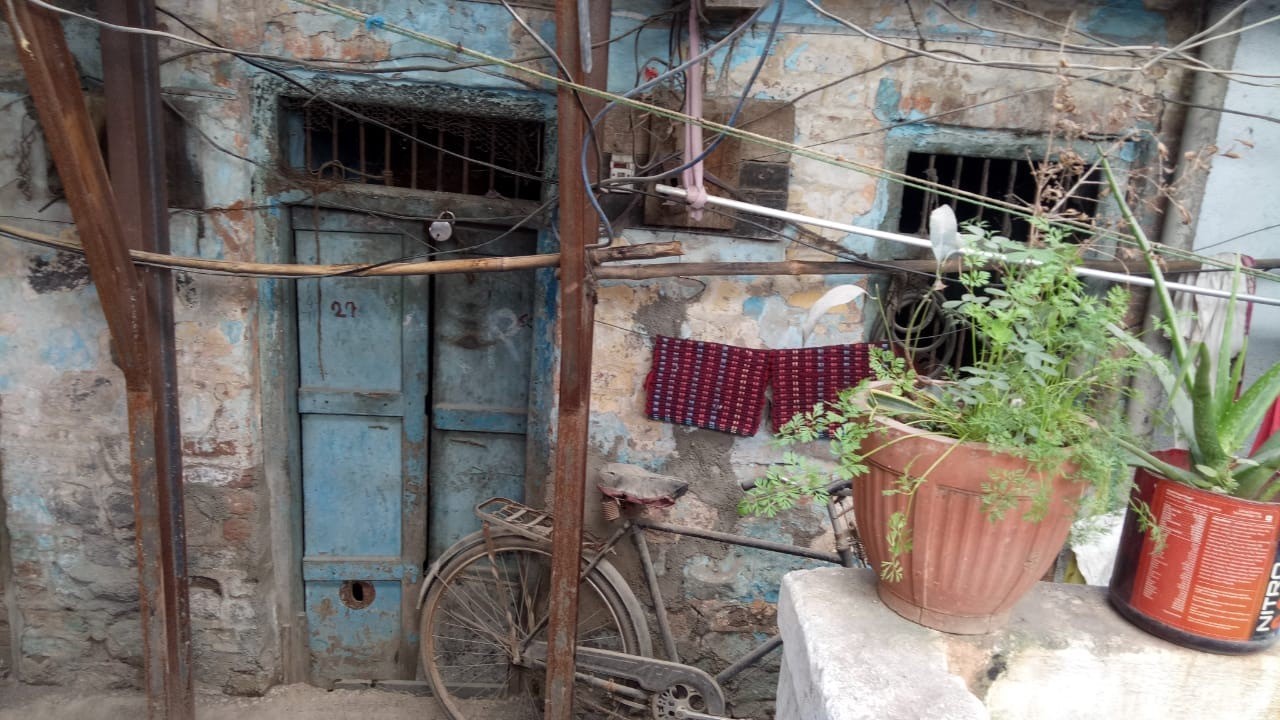 A brick structure with a doorway, bike and plants outside. 