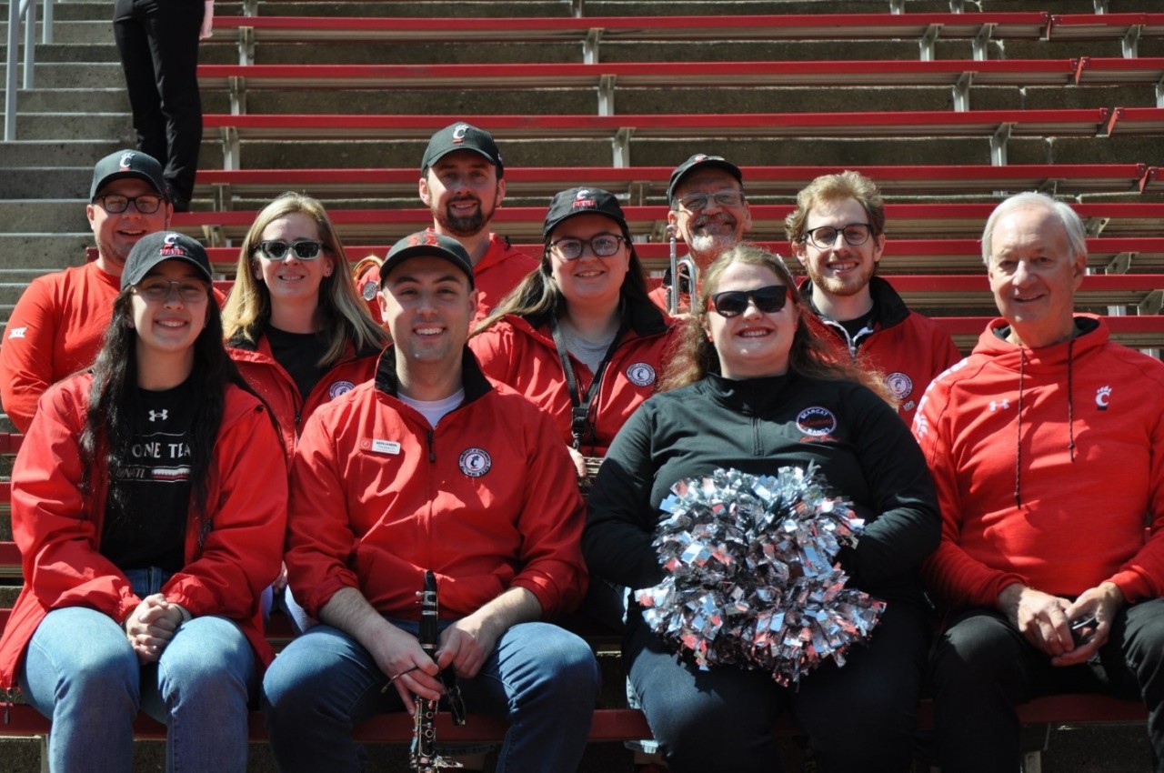 Ten people sitting in stands wearing black and red.