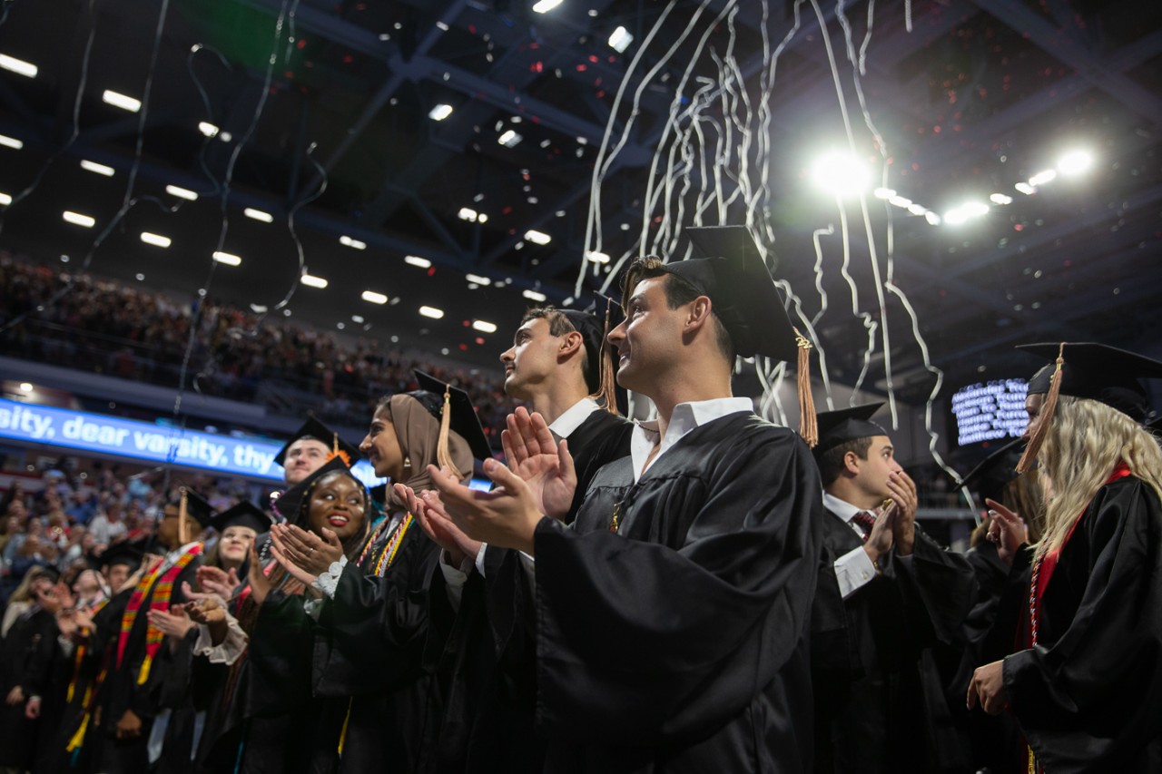 Confetti falls from the rafters onto graduates in caps and gowns at Fifth Third Arena.