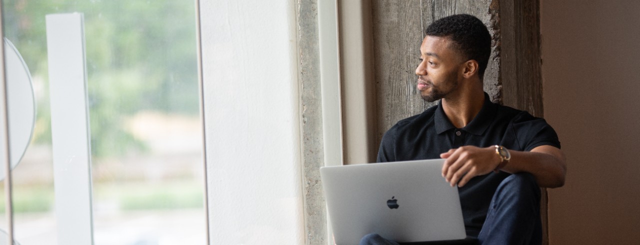 Michael Hunter sits with a laptop in his lap and looks out the window. 