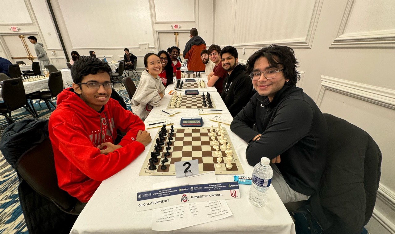 Members of UC's chess team sit at chess boards opposite members of the Ohio State University chess team.