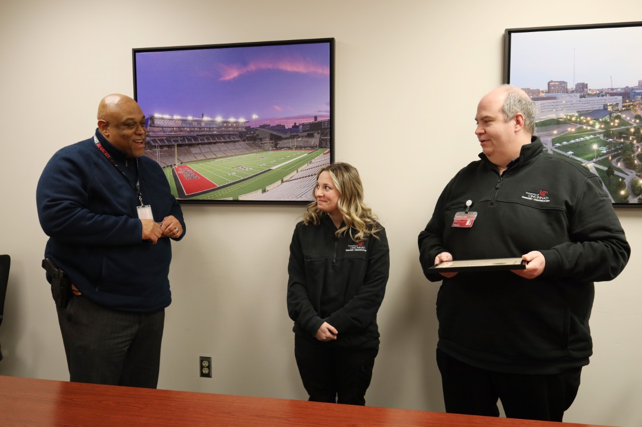 UC Public Safety Director and Chief of Police Eliot Isaac, on left, and Emergency Communications Manager Ted Langdon, on right, present Emergency Communications Dispatcher Kylee Beccaccio, middle, with the SmartSave award she received from Rave Mobile Safety.
