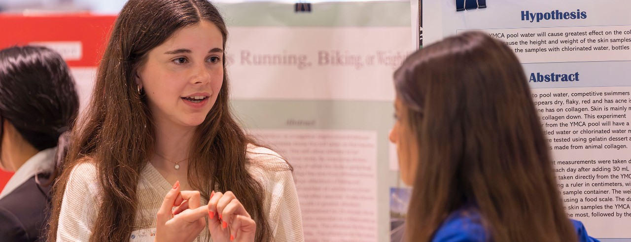 school-age student speaks with an adult at a science exhibit