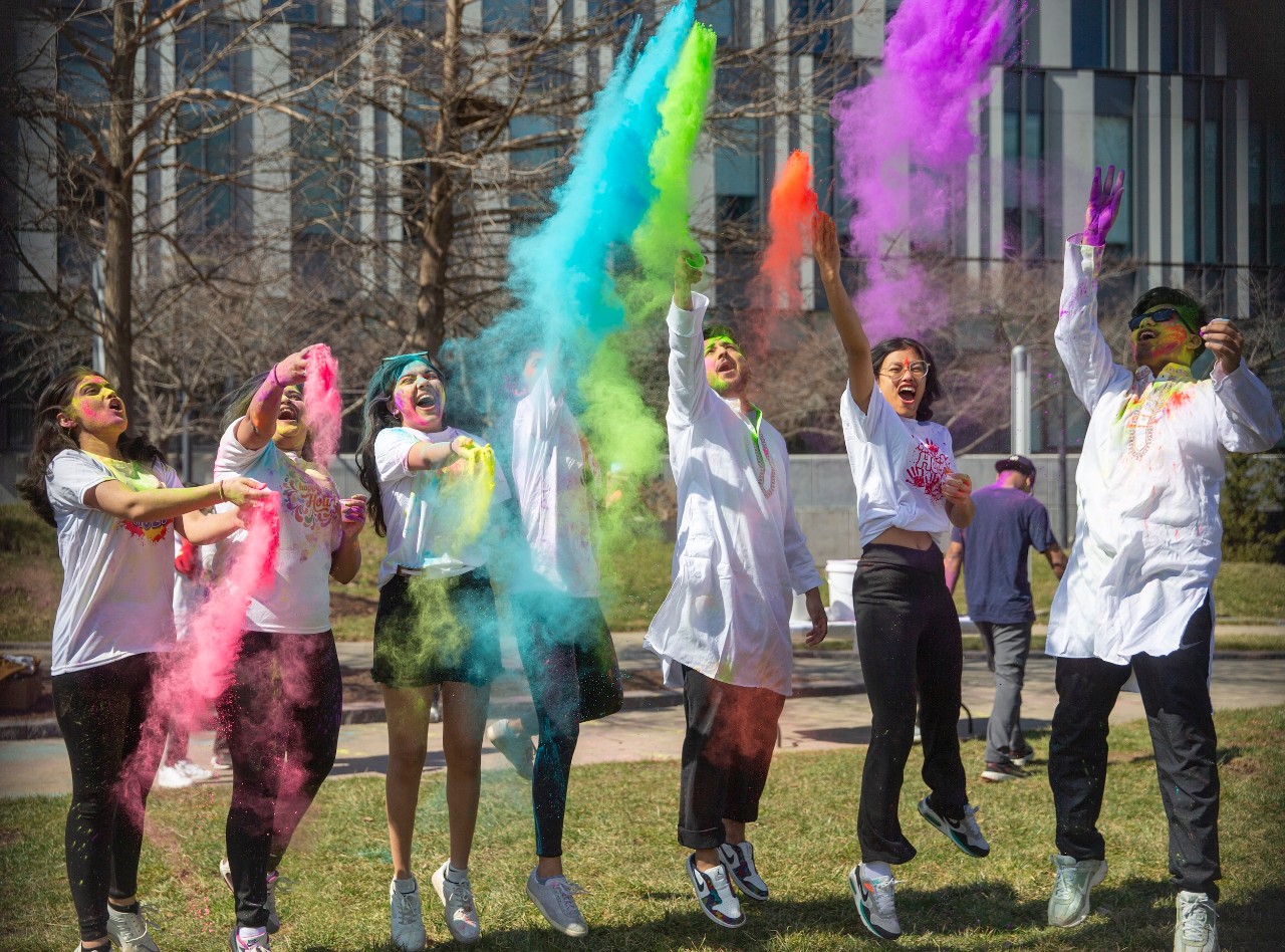 Lined up students throwing colorful powders in the air