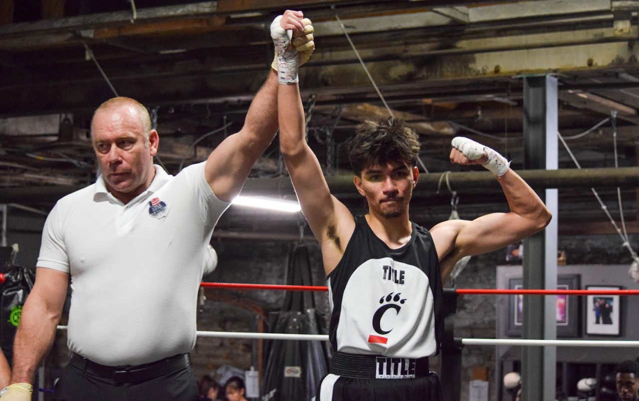 Boxing ref holds up boxer Payton Woodruff's arm in victory in the ring