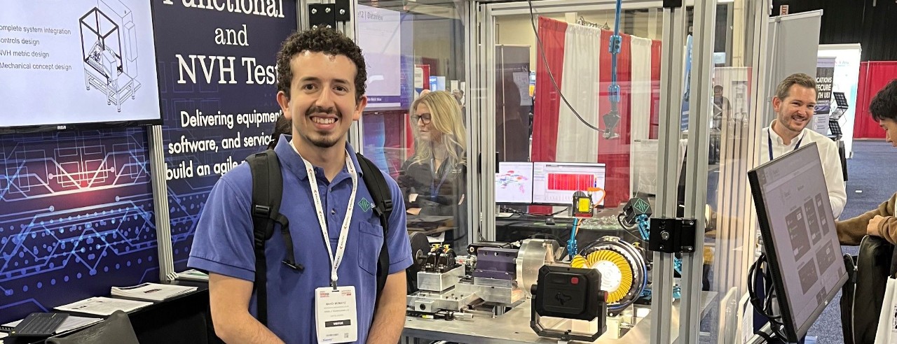 young man posing with technical machine behind him