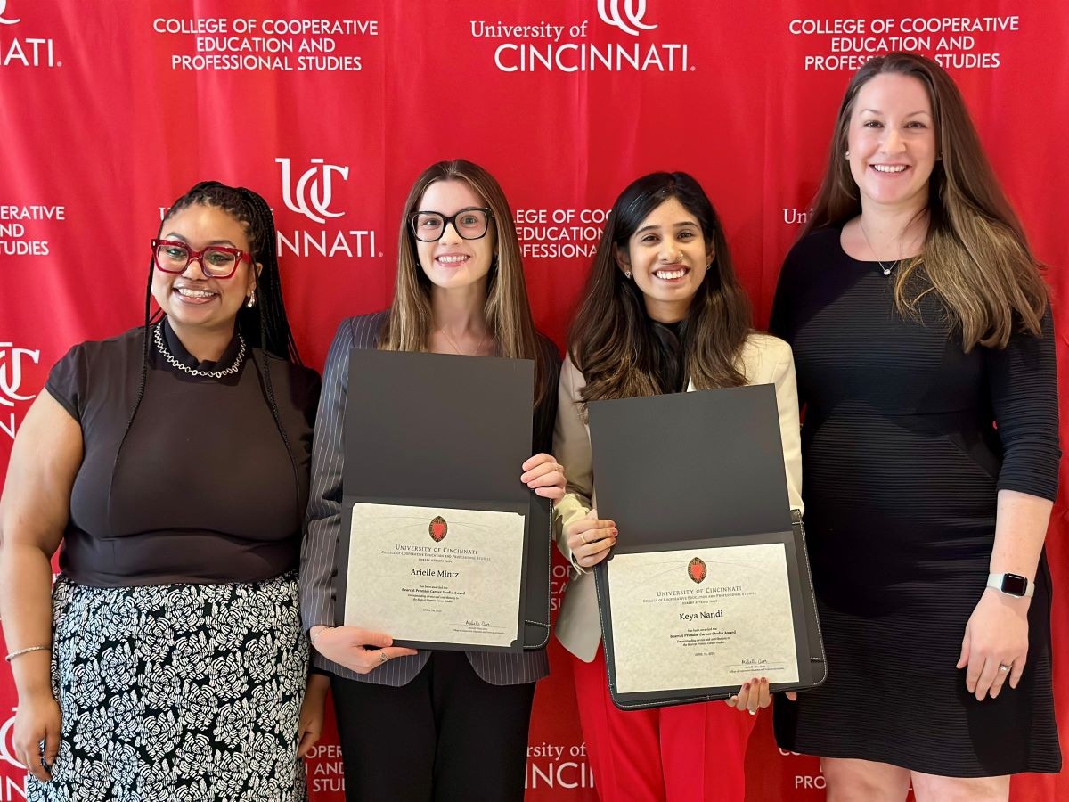 four women pose together with award certificates